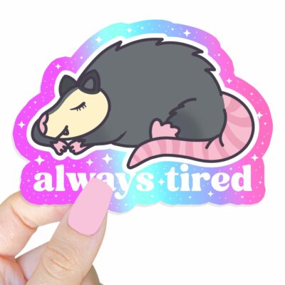 This image shows an hand-drawn adorable sticker, Always Tired Possum Sticker, which is available to purchase from HunnieByte.com