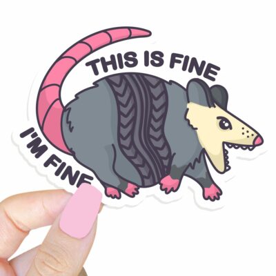 This image shows our adorable sticker finishes, This Is Fine Im Fine Possum Sticker, which is available to purchase from HunnieByte.com