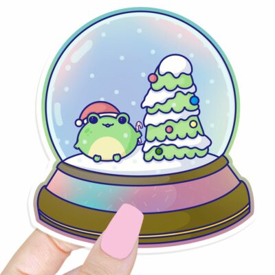 This image shows an hand-drawn adorable sticker, Holiday Frog Snowglobe Sticker, which is available to purchase from HunnieByte.com