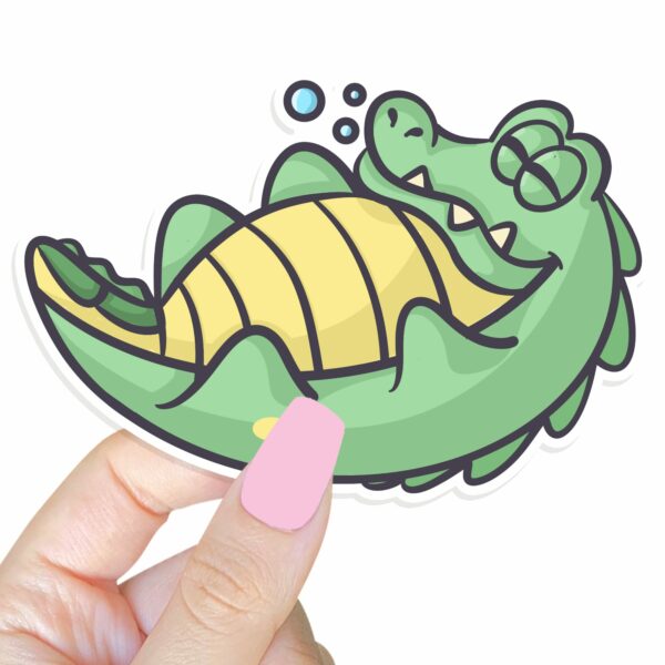 This image shows an hand-drawn adorable sticker, Lenny The Gator Sleeping Sticker, which is available to purchase from HunnieByte.com