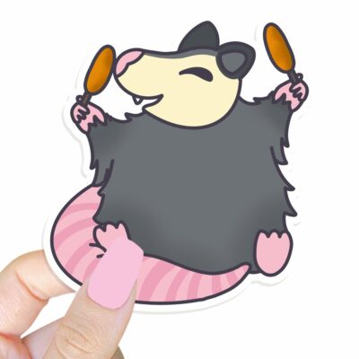 This image shows an hand-drawn adorable sticker, Corn Dog Possum Sticker, which is available to purchase from HunnieByte.com