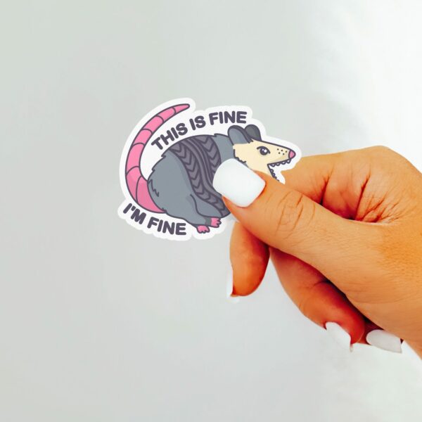 This image shows our adorable sticker finishes, This Is Fine Im Fine Possum Sticker, which is available to purchase from HunnieByte.com