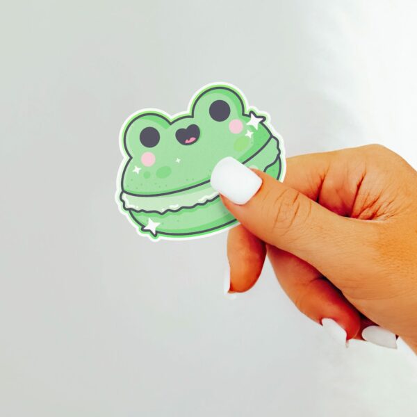 This image shows an hand-drawn adorable sticker, Frog Macaroon Sticker, which is available to purchase from HunnieByte.com