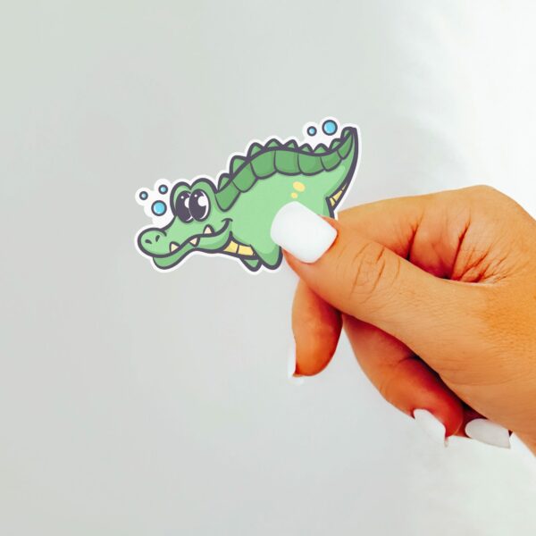 This image shows an hand-drawn adorable sticker, Lenny The Gator Swimming Sticker, which is available to purchase from HunnieByte.com