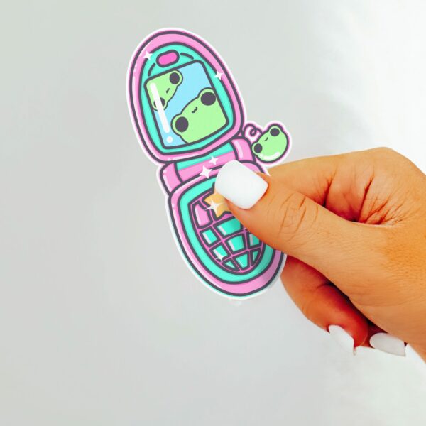 This image shows an hand-drawn adorable sticker, Froggy Flip Phone Sticker, which is available to purchase from HunnieByte.com