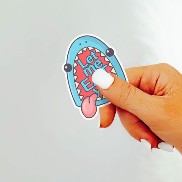 This image shows our adorable sticker finishes, Let Me Eat You Shark Sticker, which is available to purchase from HunnieByte.com