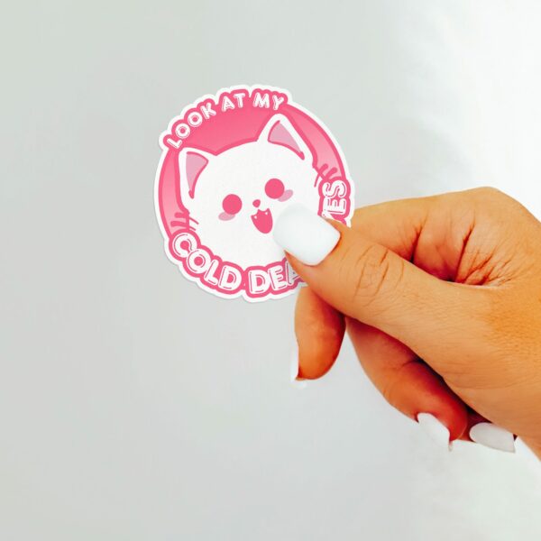 This image shows our adorable sticker finishes, Look At My Cold Dead Eyes Cat Sticker, which is available to purchase from HunnieByte.com