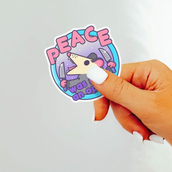 This image shows our adorable sticker finishes, Peace Was Nary An Option Possum Sticker, which is available to purchase from HunnieByte.com