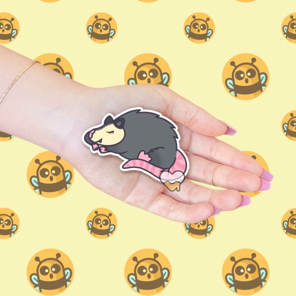 This image shows an hand-drawn adorable sticker, Sleeping Possum Sticker, which is available to purchase from HunnieByte.com