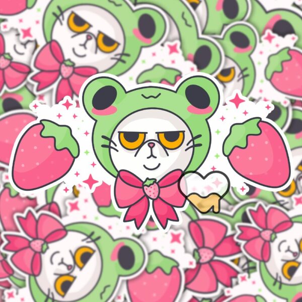 This image shows an hand-drawn adorable sticker, Grumpy Kitty with Frog Hat Sticker, which is available to purchase from HunnieByte.com