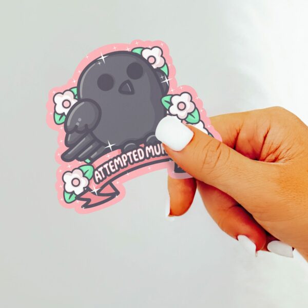 This image shows an hand-drawn adorable sticker, Attempted Murder Crow Sticker, which is available to purchase from HunnieByte.com